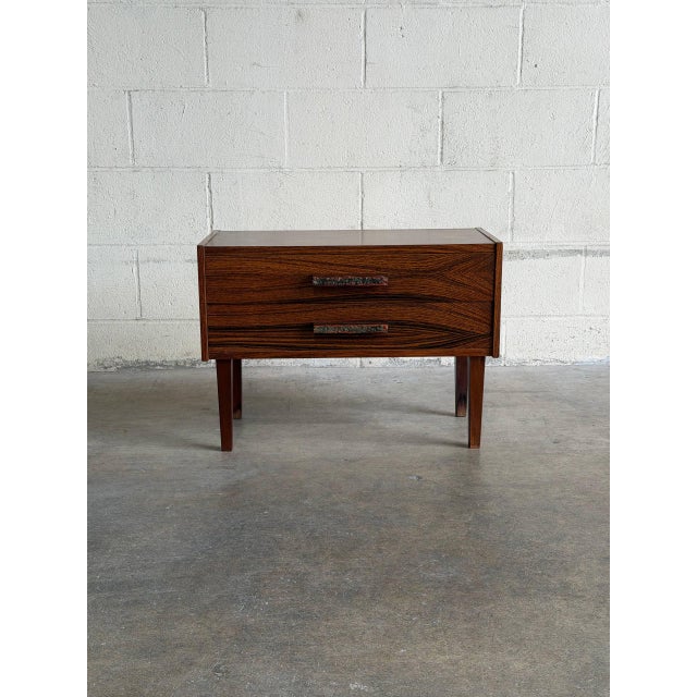 This minimalist lowboy features a compact rectangular silhouette elevated by four square tapered legs. The design...
