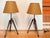 Pair of Irwin Surveyor tripod table lamps by Ralph Lauren, consisting of metal-trimmed wood legs and metal hardware. The...