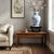 This low-profile tabletop display stand combines rich, dark-toned carved wood with a smooth, inset marble centerpiece. The...