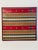 Beautifully woven and color matched textile art sample in vine red frame.