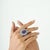 The Celestial Bloom Amethyst, Blue Topaz & Orange Sapphire Sterling Silver Cocktail Ring features a bold oval amethyst...