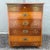 A distinctive vintage wooden jewelry or silverware chest featuring rich wood grain, decorative floral inlay, and campaign-...