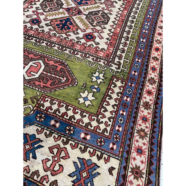 Caucasian Bordjalou Kazak design hand-knotted rug featuring a large central ivory diamond medallion filled with hooked...