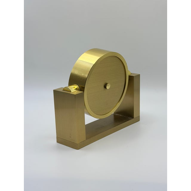 A beautifully designed Tiffany & Co. polished brass desk clock, featuring a minimalist circular case supported by a...