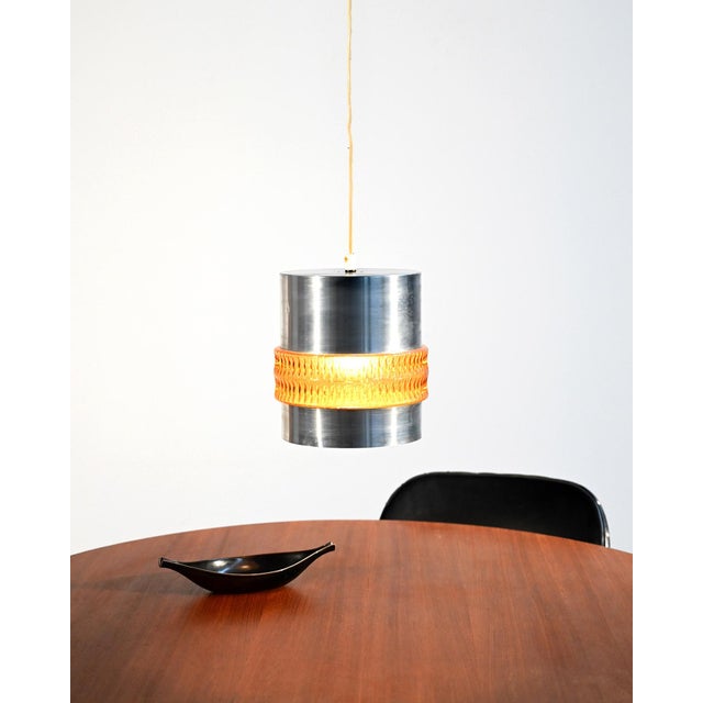 Cylindrical pendant lamp in satin-finished metal and amber-colored molded glass, produced between the 1960s and 1970s....