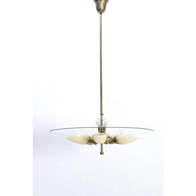 A rare italian brass pendant lamp with 5 glass shades and a bent clear glass shade above the small ones, in a remarkable...