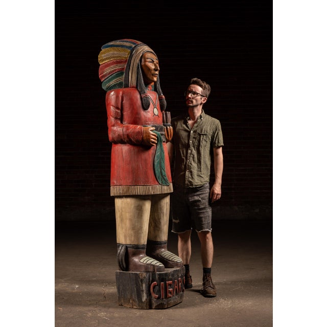 Monumental hand-carved and painted wooden figure depicting a Native American chief in traditional attire, executed in the...
