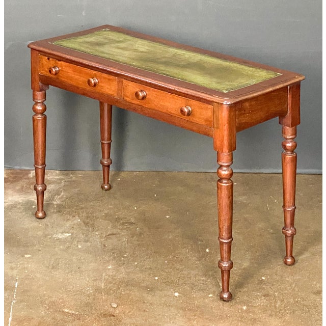 A fine English writing table or console desk of mahogany from England, featuring an inset embossed green leather top over...