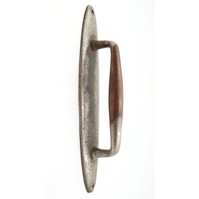 Vintage nickel plated brass door pull with a curved shaped handle and oval back plate. The original mounting screws are...