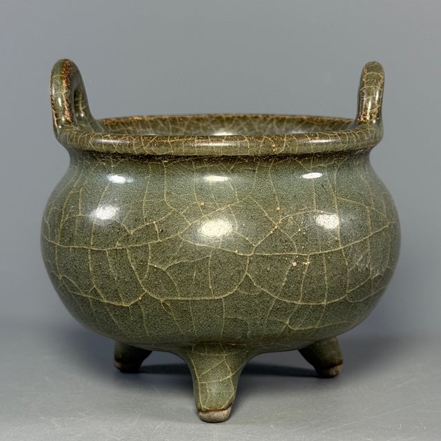 This antique Chinese tripod censer features twin upright handles and beautiful crackle celadon glaze. A fine collectible...