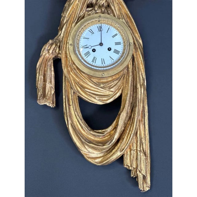 Highly sculptural Austrian Empire hand carved gilt-wood clock depicting an eagle holding a fabric piece. The center of the...