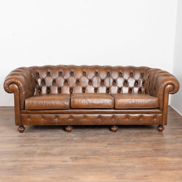 Set of (3) vintage Chesterfield-style seating including one 3-seat sofa and two matching club chairs. Brown tufted leather...