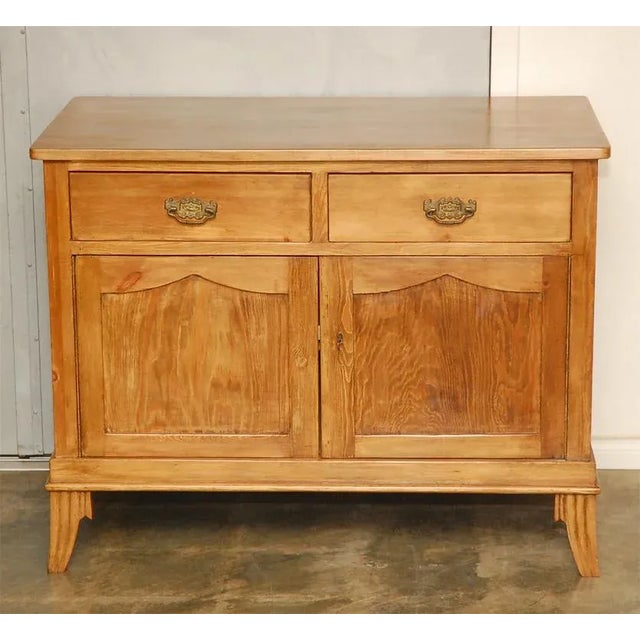 A two door and two drawer cabinet, in waxed pine, raised on carved splay legs, thought to be French and from the 1930's....