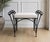 A charming vintage wrought iron vanity bench featuring an elegant neoclassical-inspired design with distinctive concentric...
