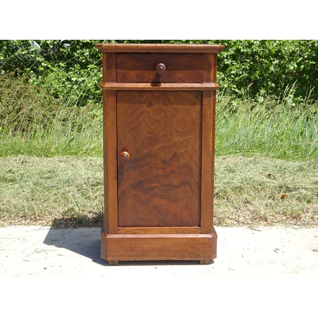 A Louis-Philippe style bedside table (mid-19th century), with clean lines, featuring a cyma recta (the rounded molding...