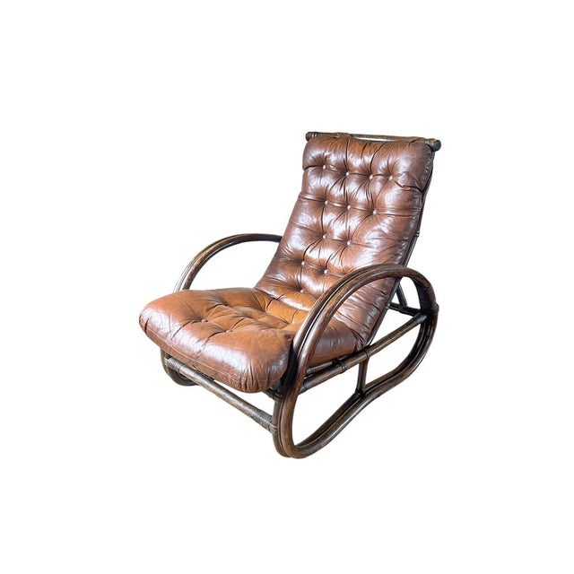 Bamboo-rattan lounge chair with an original cognac-colored leather tufted cushion. It is designed in the style of Paul T....