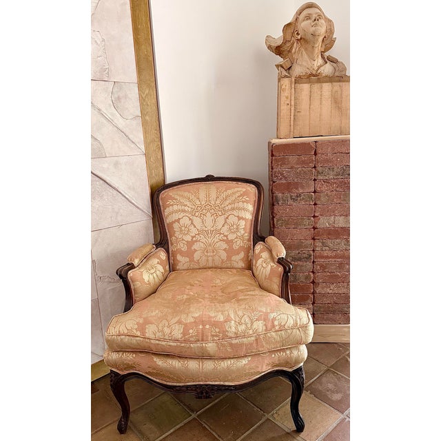 Antique Louis XV style Bergère with a shaped upholstered back, outscrolled arms, and a loose seat cushion, raised on...