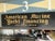 A pair of complementary trade signs for "American Marine Yacht Financing” in gold lettering on black background and...
