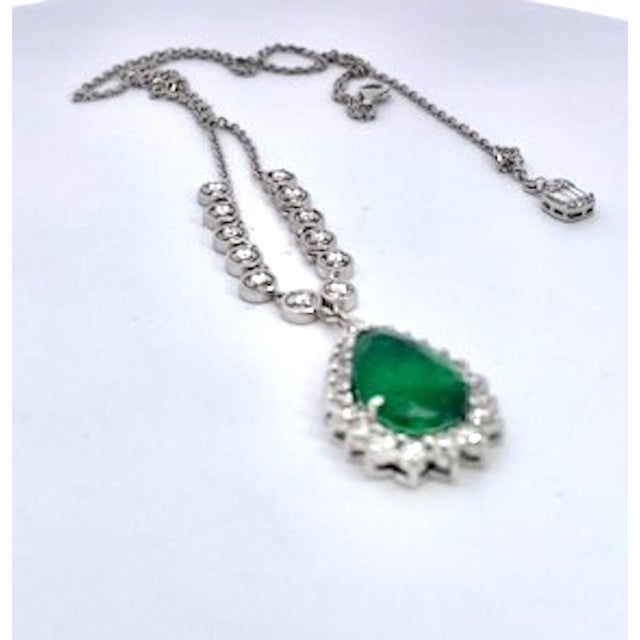 This stunning pendant necklace features a large pear-shaped emerald cabochon as its centerpiece, showcasing a rich, vivid...