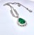 This stunning pendant necklace features a large pear-shaped emerald cabochon as its centerpiece, showcasing a rich, vivid...
