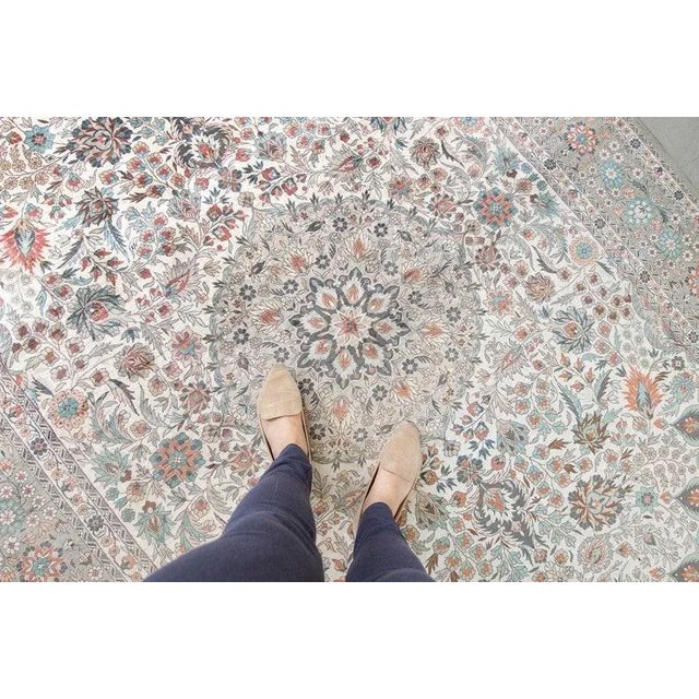 Base: green-gray/cream Accents: ivory, navy, sky blue, red, brown, beige In this rug, visible to the eye is a differing...