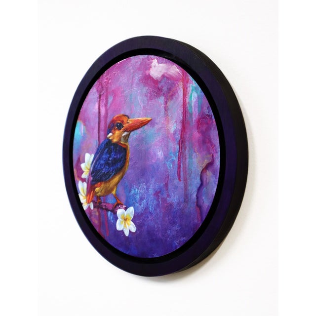 This artwork features an Oriental Pygmy Kingfisher perched on a delicate branch adorned with blossoms, set against a...