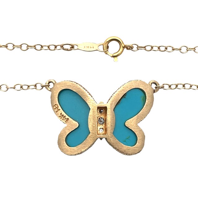 Elegant 14K yellow gold butterfly necklace featuring vibrant turquoise inlay wings and three round diamond accents at the...