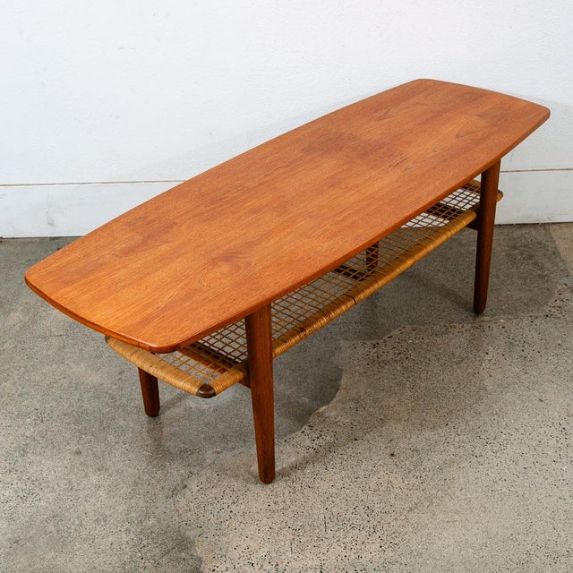 A handsome and well made Danish modern coffee table with cane wrapped shelf beneath. The top surface has been fully...