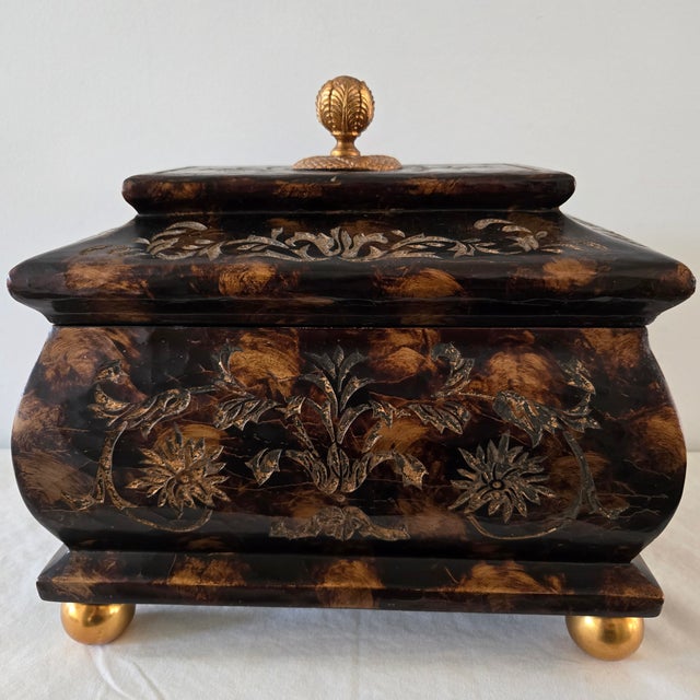 The Maitland Smith Ornate Hinged Mahogany Box with Brass Ball Feet & Finial is a large, rectangle-shaped decorative box...