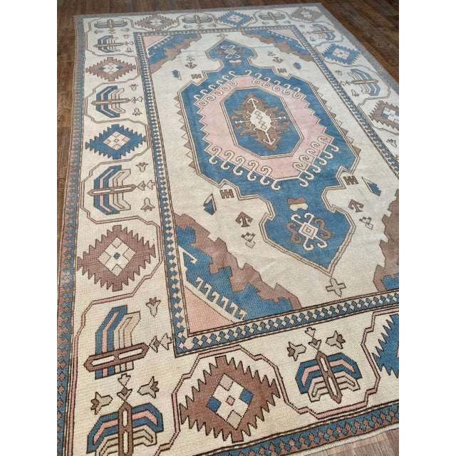 A stunning vintage Oushak rug. This vintage Oushak offers a neutral palette with blue and light pink accents.