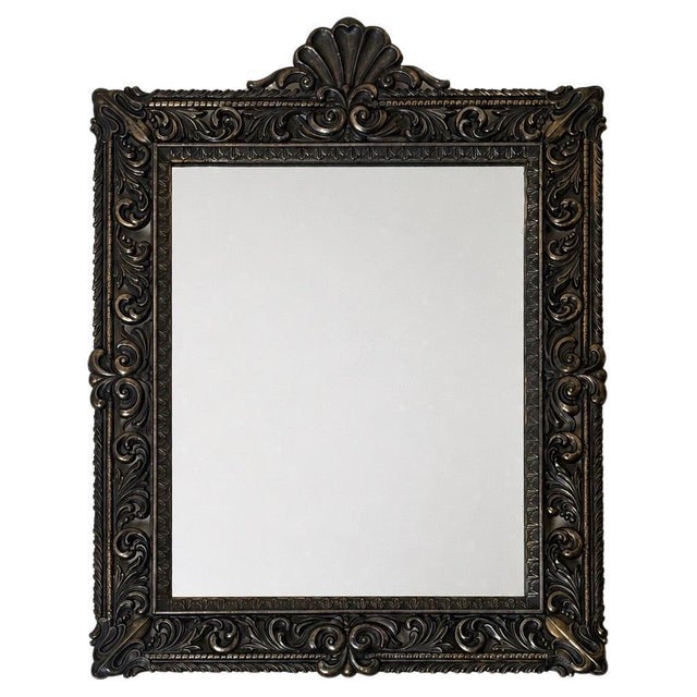 An exceptionally decorative and finely cast wall mirror of remarkable presence, featuring an elaborate ornamental frame...