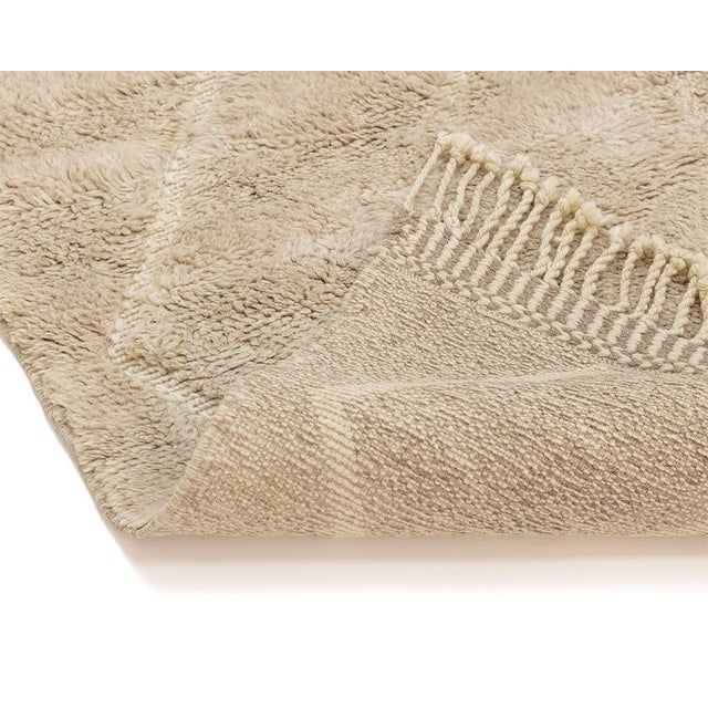 Elegant hand-knotted wool rug in Beige, adorned with subtle asymmetrical diamond patterns, offering a chic and versatile...