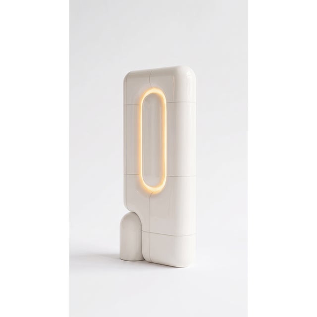 The vertical one. Where the rest of the collection sits low and grounded, this table lamp rises in a slim column of curved...