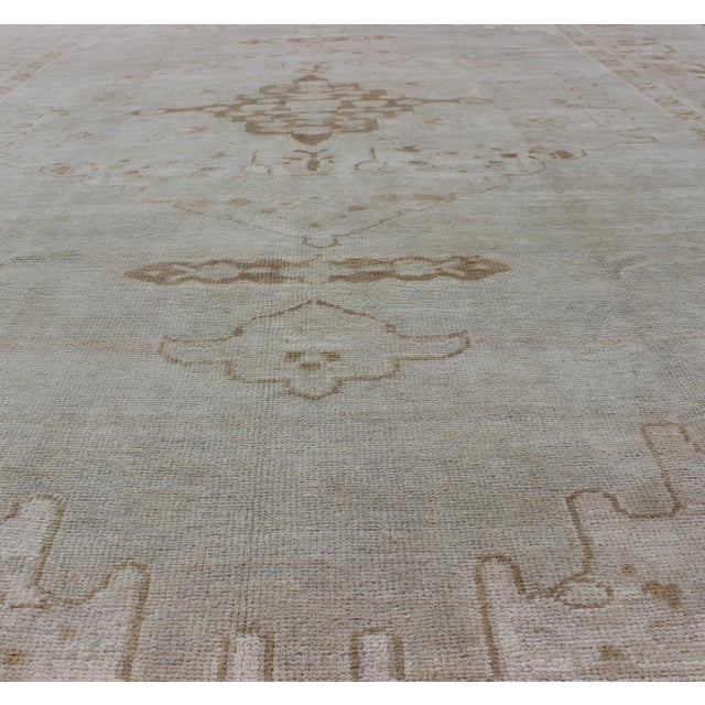 Measures: 7'3'' x 11'2''. This vintage Oushak carpet beautifully integrates neutral color compositions to decorate a calm...