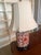 This elegant table lamp features a classic Chinoiserie-style porcelain base decorated with intricate red floral patterns...