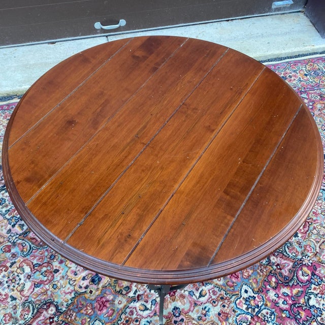 High quality round center table by Nichols & Stone featuring a planked solid wood top on a hand forged wrought iron base...