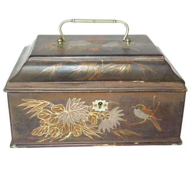 An vintage Japanese jewelry box crafted from metal, depicting a bird on a branch surrounded by foliage, embodies a refined...
