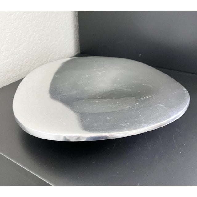 Cast aluminum centerpiece bowl with sinuous, organic form and polished mirrored metal finish. Designed by sculptor and...