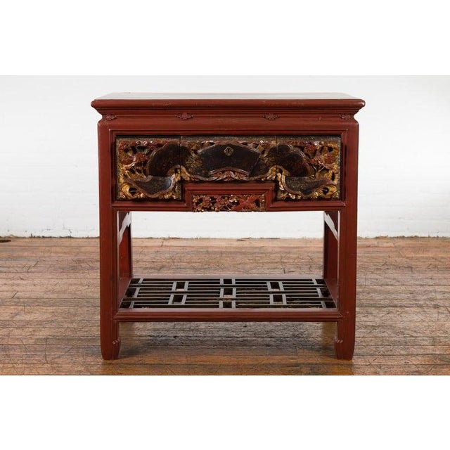 A Chinese red lacquered console table from the 20th century made with 19th century carved pieces, with very unusual hand...