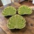 The product is a set of three ceramic serving plates in the shape of green Monstera leaves, designed by the brand...