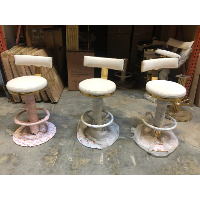 Bring the Old Hollywood Glamour to your space with these Art Deco swivel gold counter chairs upholstered with white...