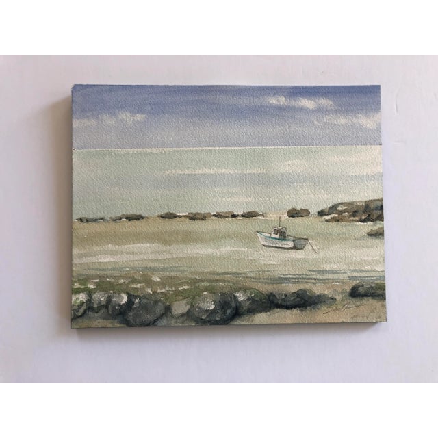 A boat moored in the shallows, kept safe by a row of rocks. A peaceful scene. Signed and ready to frame.