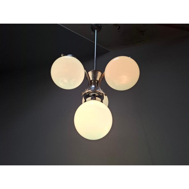 Original Art Deco chandelier manufactured in Czechoslovakia during the 1930s. The fixture features four spherical opaline...