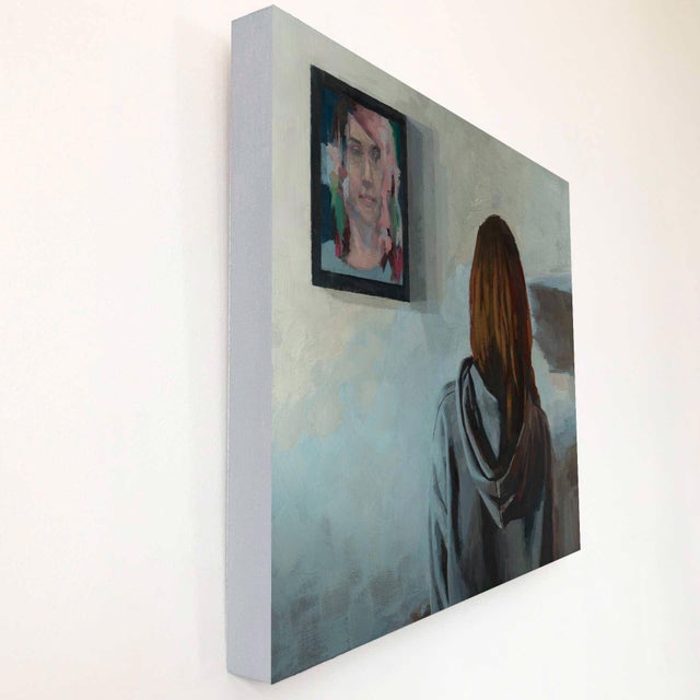 This oil painting depicts a figure with their back turned, gazing contemplatively at a portrait on the wall. The muted...