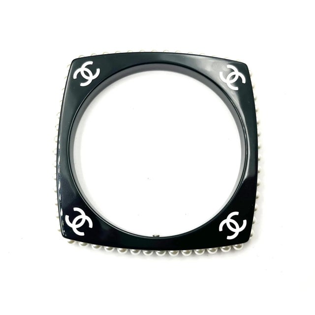 This is part of Chairish’s Costume Jewelry assortment. Chanel White CC Black Resin Pearl Edge Bangle Bracelet *Marked 15...