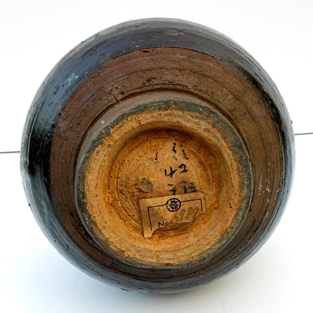 Buff red stoneware vase with a pear form, finished in a dark mottled brown glaze that stops short of the foot, typical of...