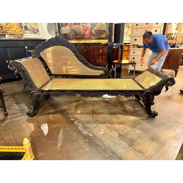 The 19th c. British Colonial Carved Ebony Chaise is a stunning piece of antique furniture. This original chaise features...