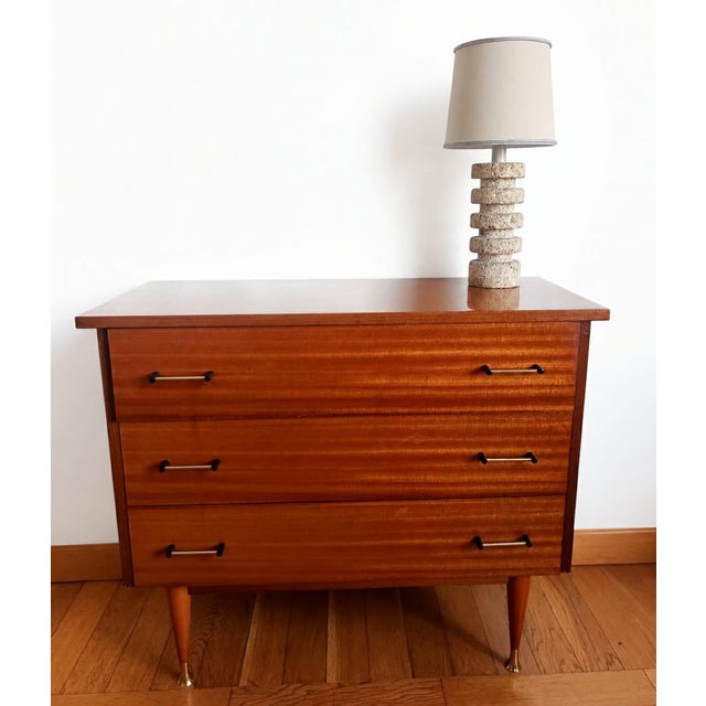Vintage Scandinavian-style chest of drawers with splayed legs and brass-plated feet. High-gloss lacquered wood, three...