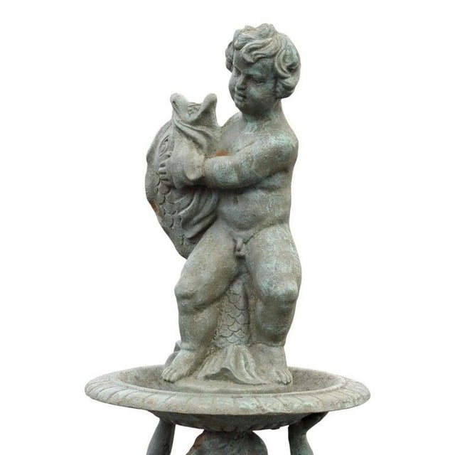 This vintage cast iron garden fountain features a tiered design with figural elements. The top tier showcases a cherubic...