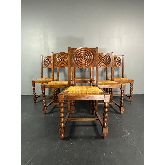 Lovely set of 6 dining chairs wood turned legs with rush seats in the style of Charles Dudouyt. This set most likely is...